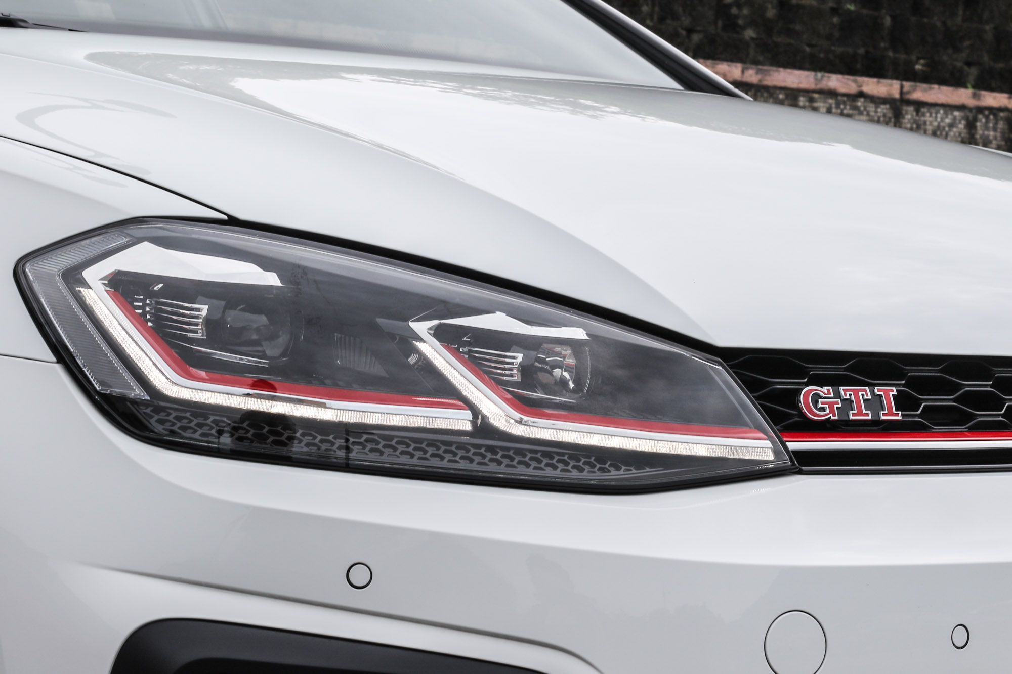 連貫頭燈與水箱護罩的紅色飾條強調性能本質，頭尾與車側皆有 GTI 字樣。