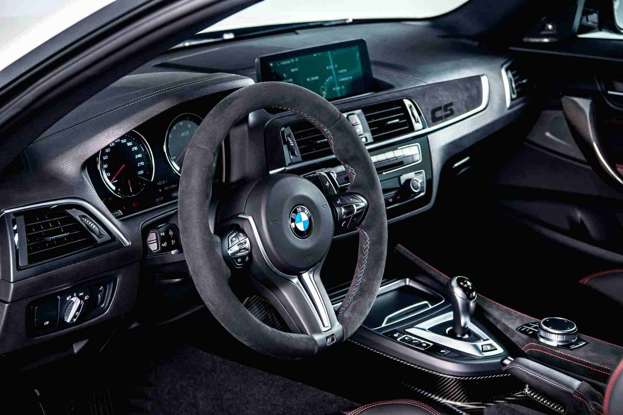 全新 BMW M2 CS 處處可見 Alcantara 麂皮材質與對比紅色縫線設計，副駕駛座前方更鑲上專屬的紅色「CS」字樣。